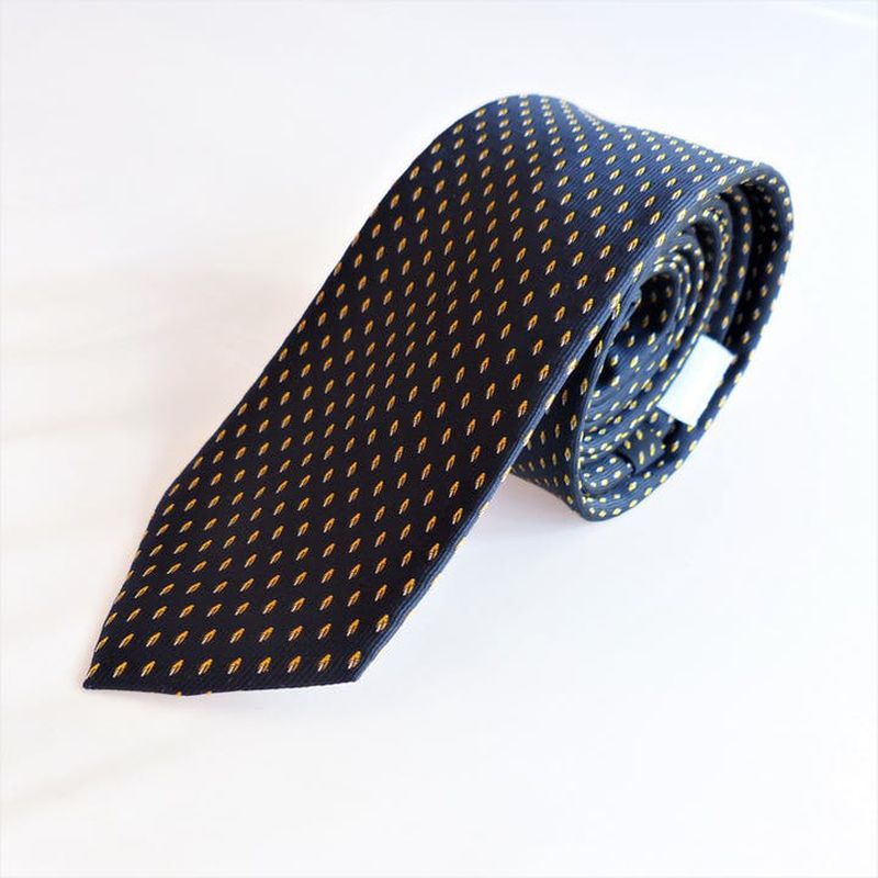 Corbata azul marino con motas en color amarillo, fabricada en Italia. Limpieza en seco. 145 cm x 6 cm. Jacquard 100% Poliéster. Regalo caballero elegante y clásico.